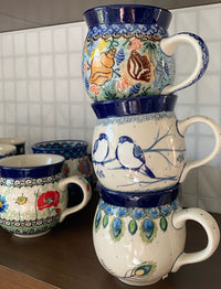 A picture of a Polish Pottery CA 12 oz. Belly Mug (Bullfinch on Blue) | A070-U4830 as shown at PolishPotteryOutlet.com/products/12-oz-belly-mug-bullfinch-on-blue-a070-u4830