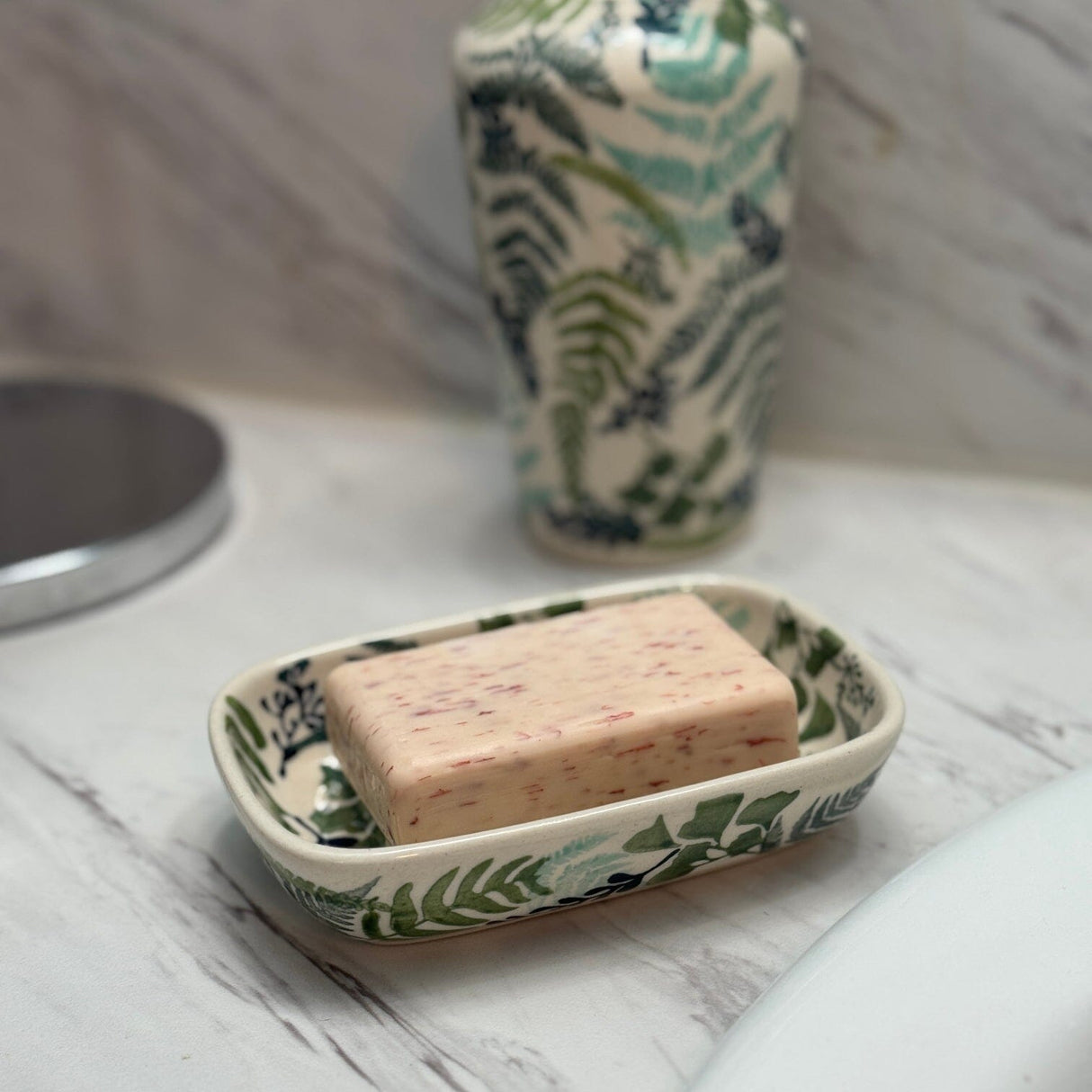Bar of soap in a decorative soap dish on a marble surface
