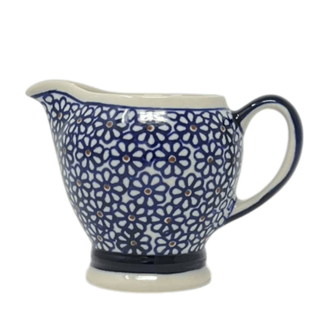 Ceramic creamer with blue floral pattern on a white background