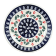 Ceramic plate with festive design featuring holly leaves and berries on a white background
