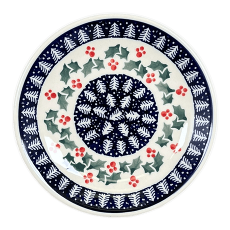 Ceramic plate with festive design featuring holly leaves and berries on a white background