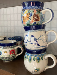 A picture of a Polish Pottery C.A. 16 oz. Belly Mug (Bullfinch on Blue) | A073-U4830 as shown at PolishPotteryOutlet.com/products/large-belly-mug-bullfinch-on-blue-a073-u4830